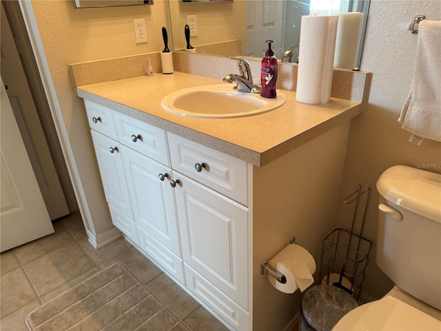 bathroom with toilet, tile patterned flooring, and vanity