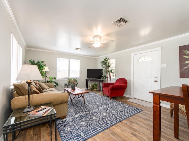 living area with ornamental molding, wood finished floors, and visible vents