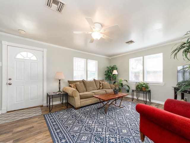 living area featuring ornamental molding, visible vents, baseboards, and wood finished floors