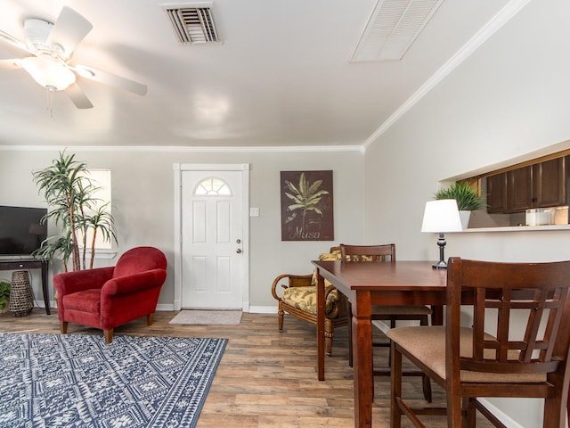 dining room featuring baseboards, wood finished floors, visible vents, and crown molding