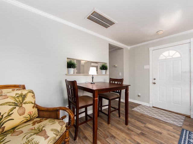 dining space featuring ornamental molding, wood finished floors, visible vents, and baseboards