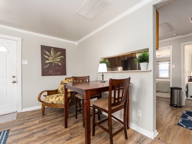 dining room with baseboards, crown molding, visible vents, and wood finished floors