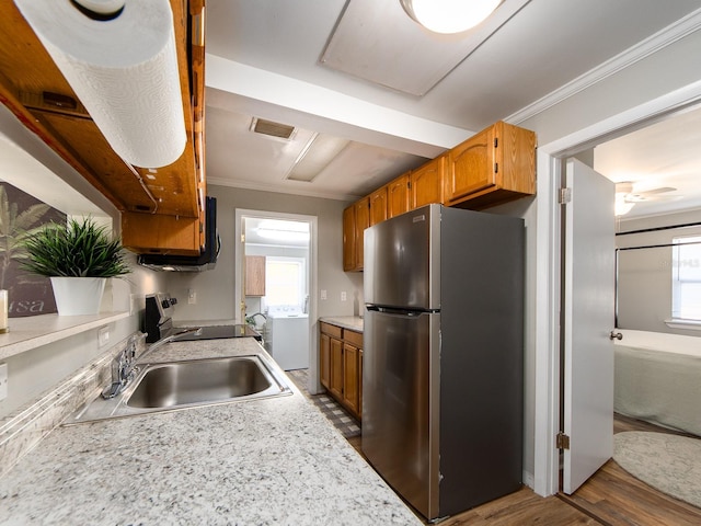 kitchen with visible vents, stove, freestanding refrigerator, light countertops, and a sink