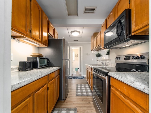 kitchen featuring electric range, visible vents, light stone countertops, black microwave, and a sink