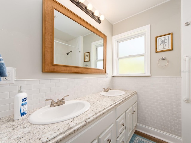 bathroom with wainscoting, a sink, tile walls, and double vanity