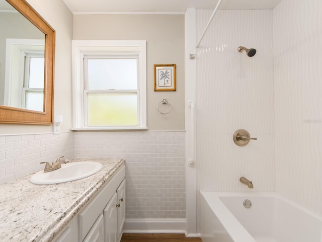 bathroom featuring tile walls, wainscoting, vanity, and shower / tub combination