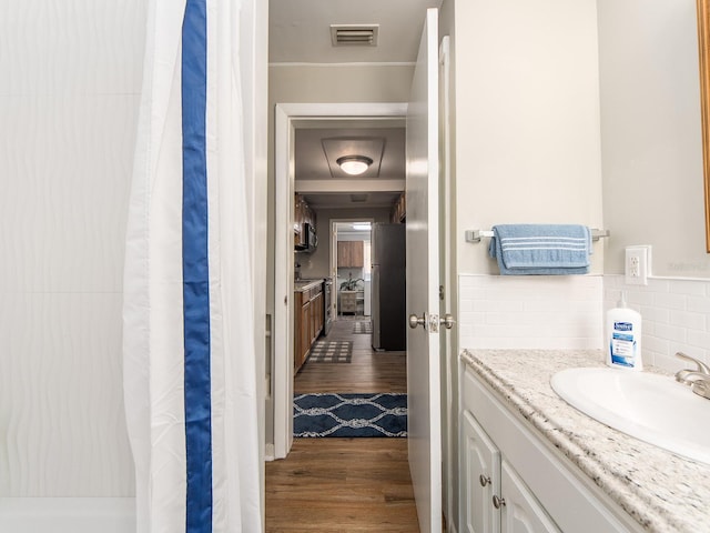 full bathroom with curtained shower, wood finished floors, vanity, visible vents, and tasteful backsplash