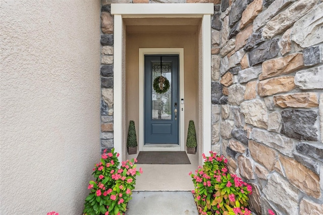 entrance to property featuring stone siding and stucco siding