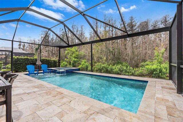 view of pool featuring glass enclosure, a pool with connected hot tub, and a patio