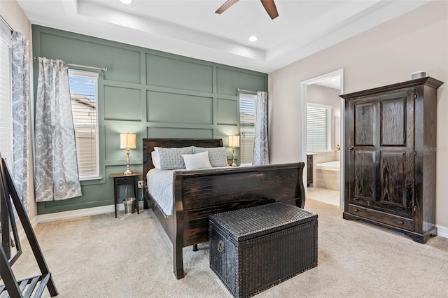 bedroom featuring recessed lighting, a raised ceiling, light carpet, and a decorative wall