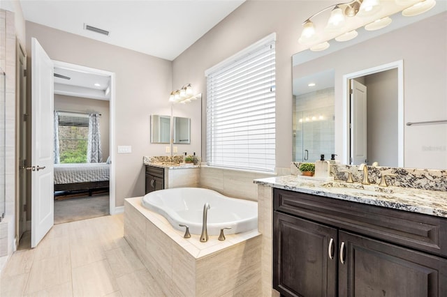 ensuite bathroom with visible vents, ensuite bathroom, a sink, a garden tub, and two vanities