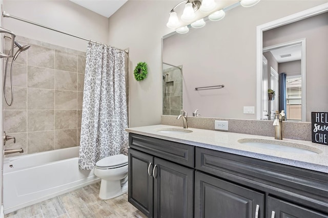 full bathroom with shower / tub combo with curtain, a sink, toilet, and wood finished floors