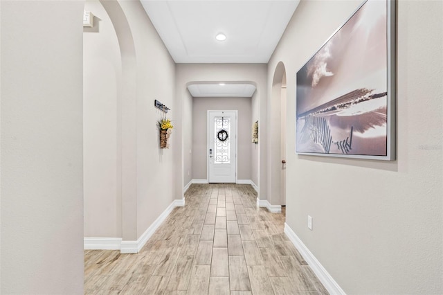 entryway featuring arched walkways, baseboards, and wood finished floors