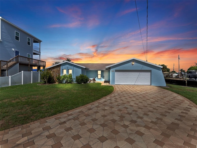 view of front of house with a balcony, an attached garage, fence, decorative driveway, and a front yard