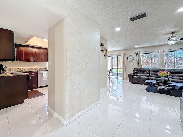 living area featuring light tile patterned floors, visible vents, a textured ceiling, and a textured wall