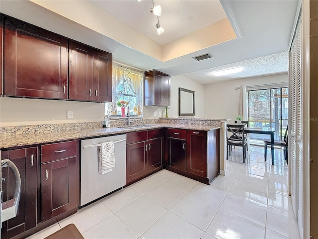 kitchen featuring dishwasher, a tray ceiling, a sink, and a wealth of natural light