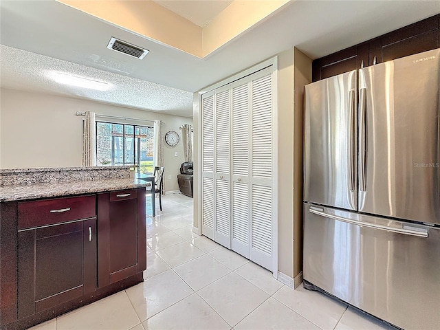 kitchen with light tile patterned floors, visible vents, a textured ceiling, and freestanding refrigerator