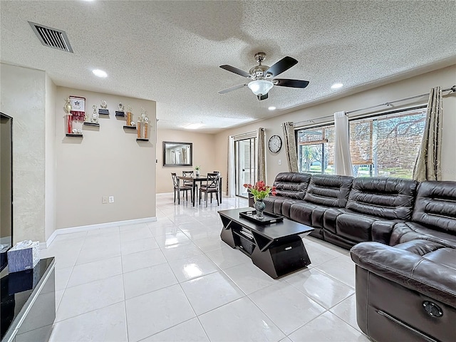 living area with a ceiling fan, visible vents, a textured ceiling, and light tile patterned flooring