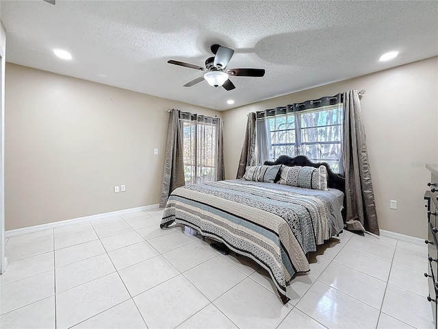 bedroom featuring ceiling fan, a textured ceiling, baseboards, and light tile patterned floors