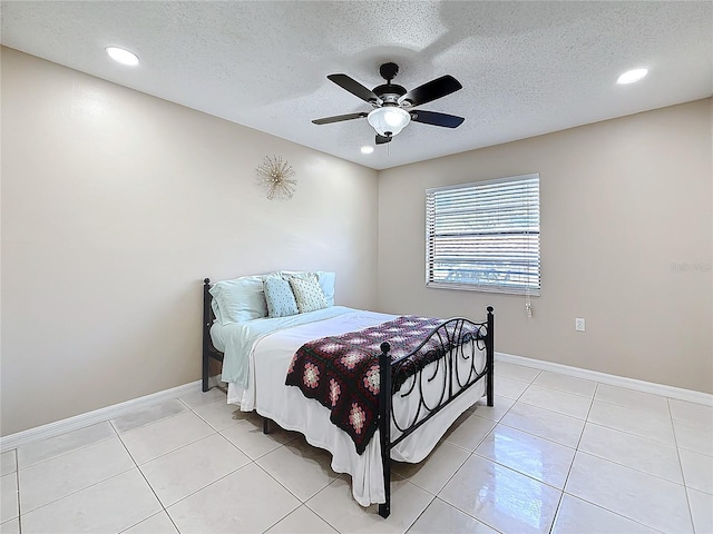 bedroom featuring light tile patterned floors, ceiling fan, baseboards, and a textured ceiling