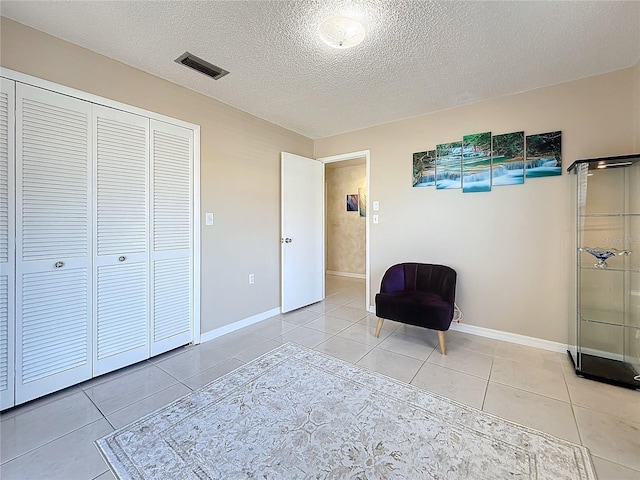 unfurnished room with baseboards, visible vents, a textured ceiling, and light tile patterned flooring