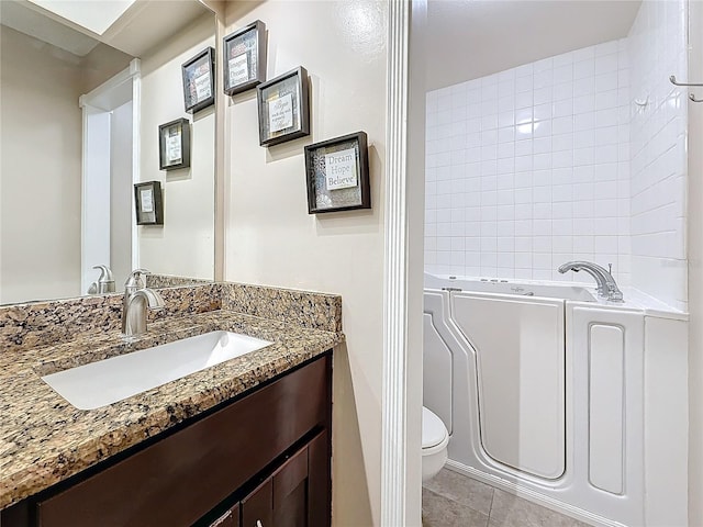 bathroom with a tub to relax in, vanity, toilet, and tile patterned floors