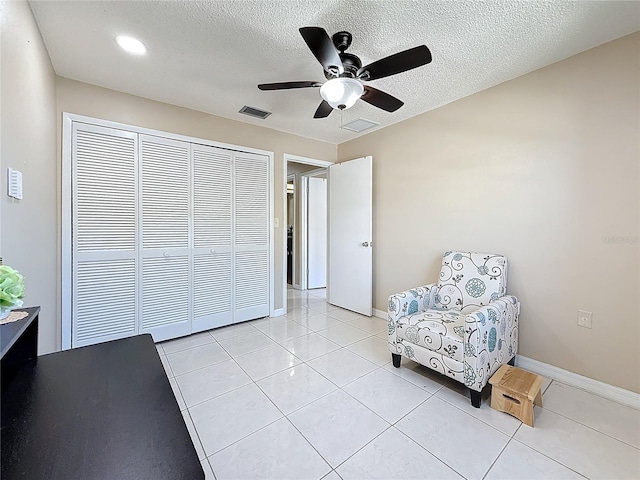 living area with baseboards, visible vents, a textured ceiling, and light tile patterned flooring