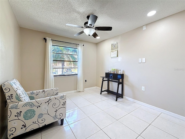 sitting room featuring a ceiling fan, a textured ceiling, baseboards, and light tile patterned floors