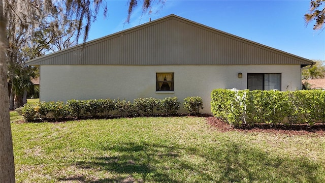 view of side of property with a lawn and stucco siding