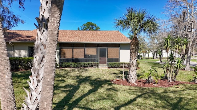 back of house with a yard, a sunroom, and stucco siding