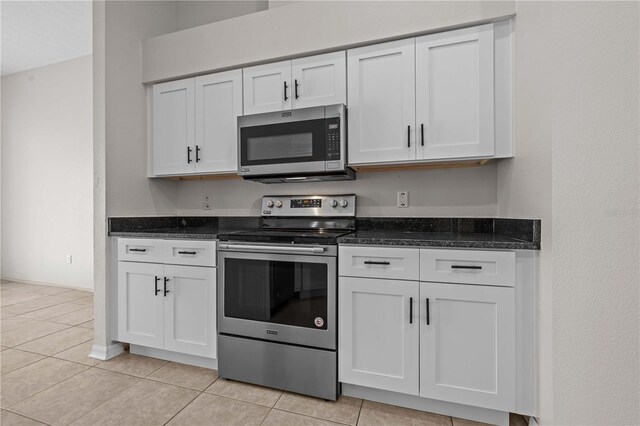 11611 Jordans Landing Ct, Riverview, FL 33569 - kitchen featuring appliances with stainless steel finishes, white cabinetry, light tile patterned floors, dark stone countertops, and baseboards