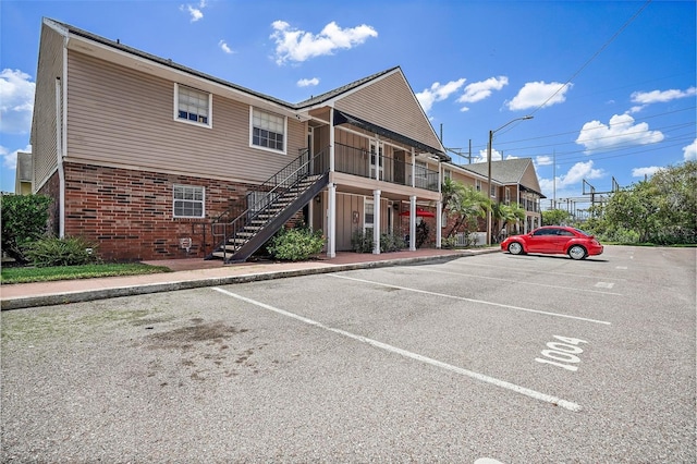 view of building exterior featuring stairs and uncovered parking