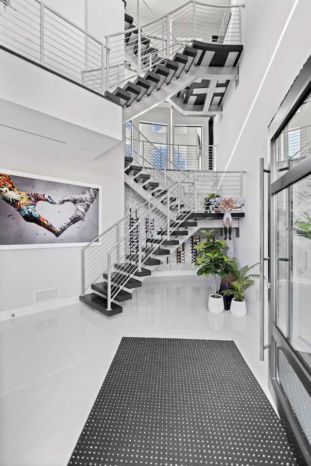 stairway with a high ceiling and tile patterned floors