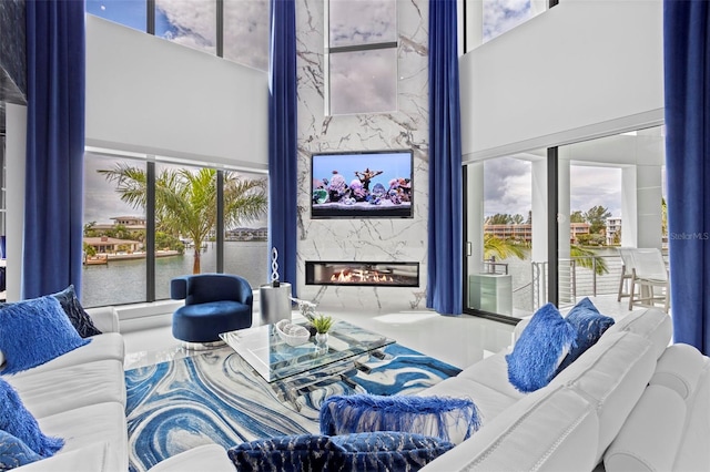 living area featuring a towering ceiling, a water view, a fireplace, and a wealth of natural light