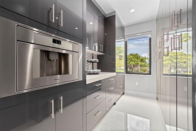 kitchen featuring light tile patterned floors, modern cabinets, baseboards, and light countertops