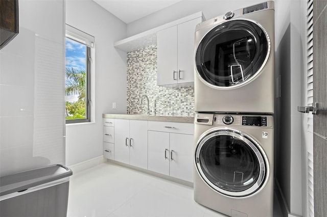 laundry area featuring stacked washer and dryer, a sink, and light tile patterned flooring