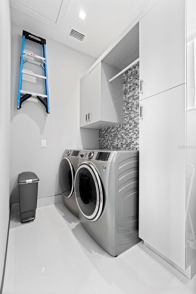 laundry area featuring washer and dryer, cabinet space, and visible vents