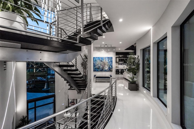 corridor with recessed lighting, marble finish floor, and stairway