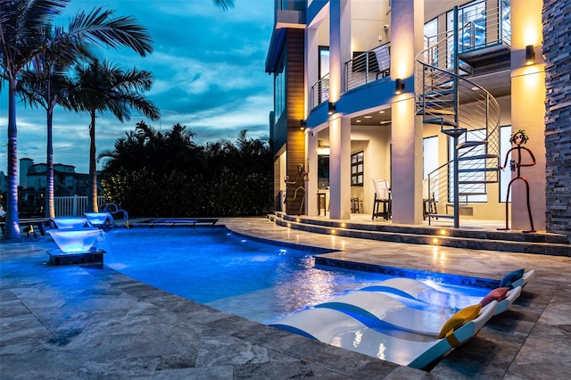 outdoor pool featuring stairway and a patio