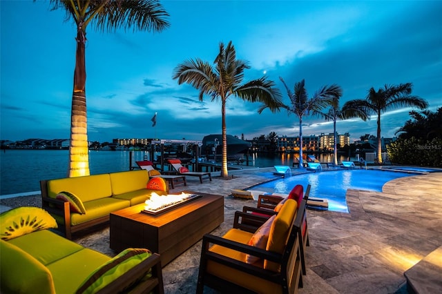 view of swimming pool featuring a patio area, an outdoor living space with a fire pit, and a water view