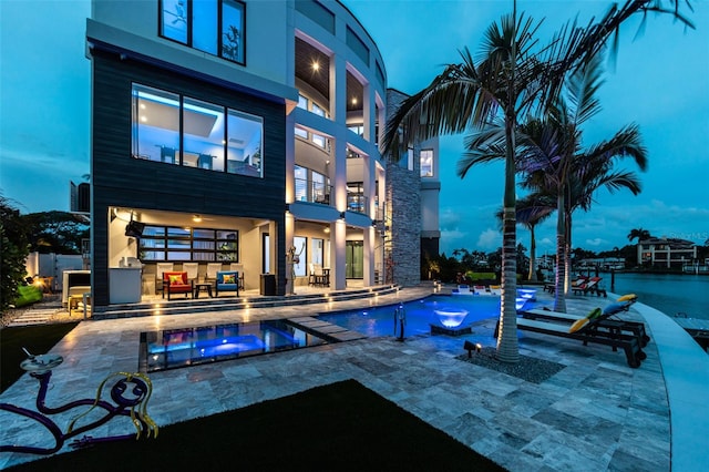 rear view of house with a patio area, an outdoor pool, and an in ground hot tub