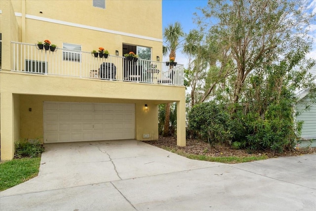 exterior space with a garage, a balcony, concrete driveway, and stucco siding