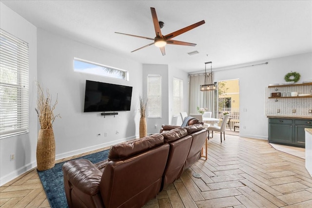 living room with baseboards, visible vents, and ceiling fan