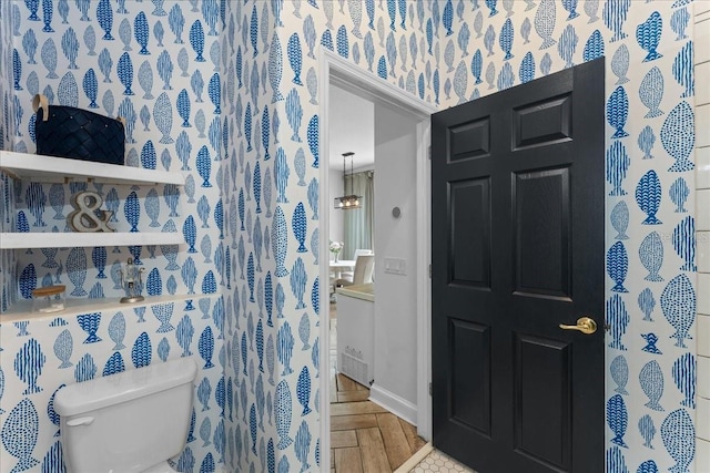 bathroom with baseboards, toilet, and wallpapered walls