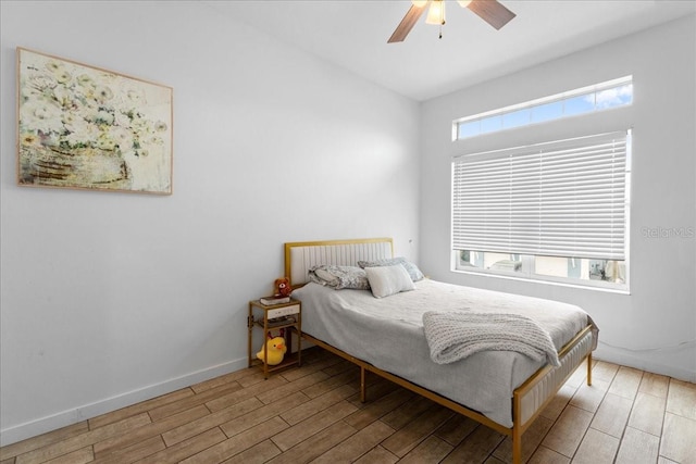 bedroom with a ceiling fan, multiple windows, baseboards, and wood finished floors