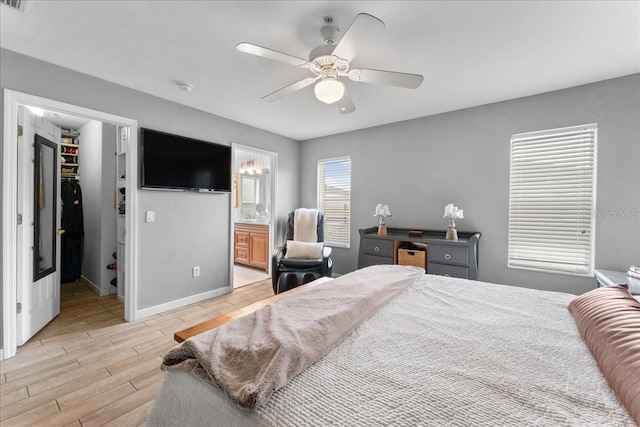 bedroom with baseboards, ceiling fan, a spacious closet, light wood-style floors, and a closet