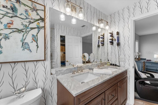 bathroom with vanity, toilet, and wallpapered walls