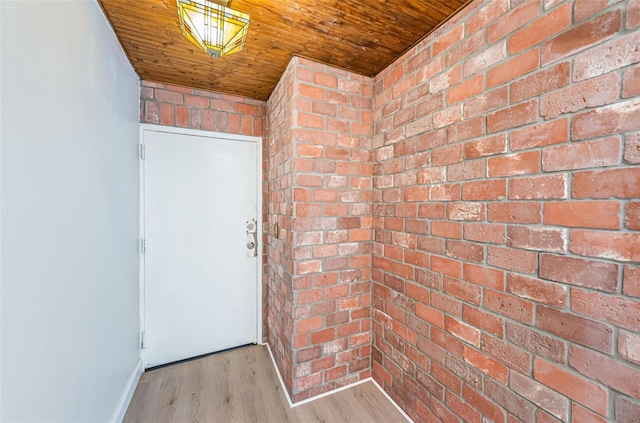 doorway to outside with brick wall, wood ceiling, and wood finished floors