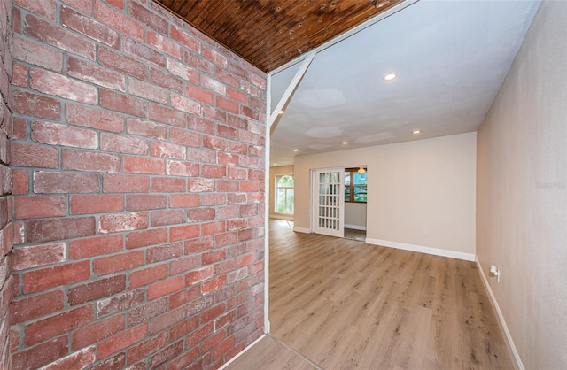 empty room featuring recessed lighting, brick wall, baseboards, and wood finished floors