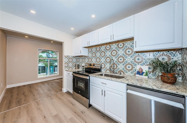 kitchen with light stone counters, stainless steel appliances, a sink, white cabinets, and backsplash